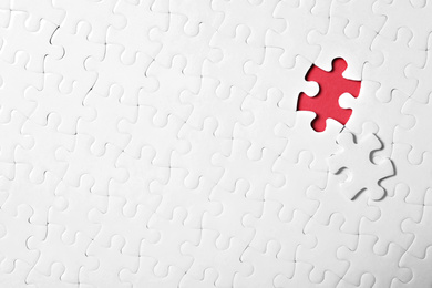 Photo of Blank white puzzle with separated piece on red background, top view. Space for text