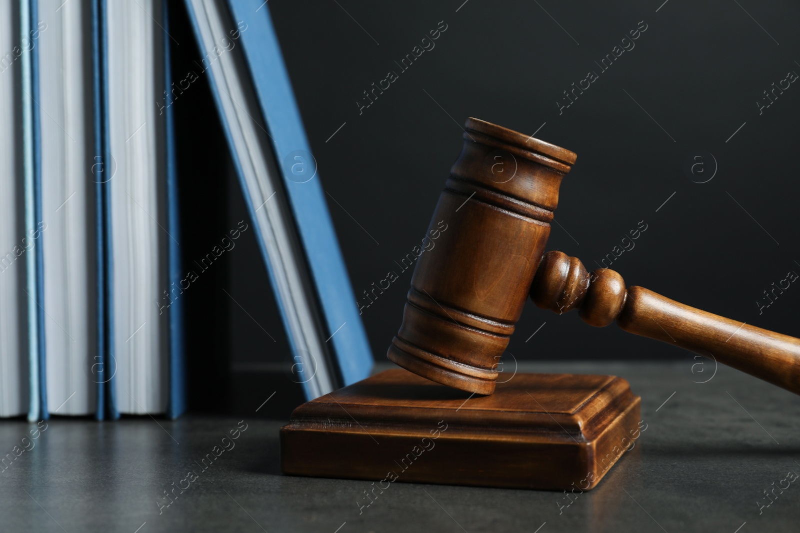 Photo of Wooden gavel and books on table against dark background. Law concept