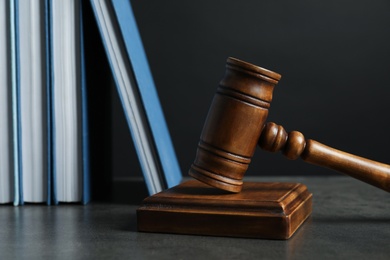 Photo of Wooden gavel and books on table against dark background. Law concept