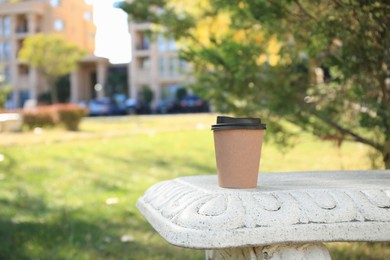 Photo of Cardboard cup with tasty coffee on stone bench outdoors. Space for text