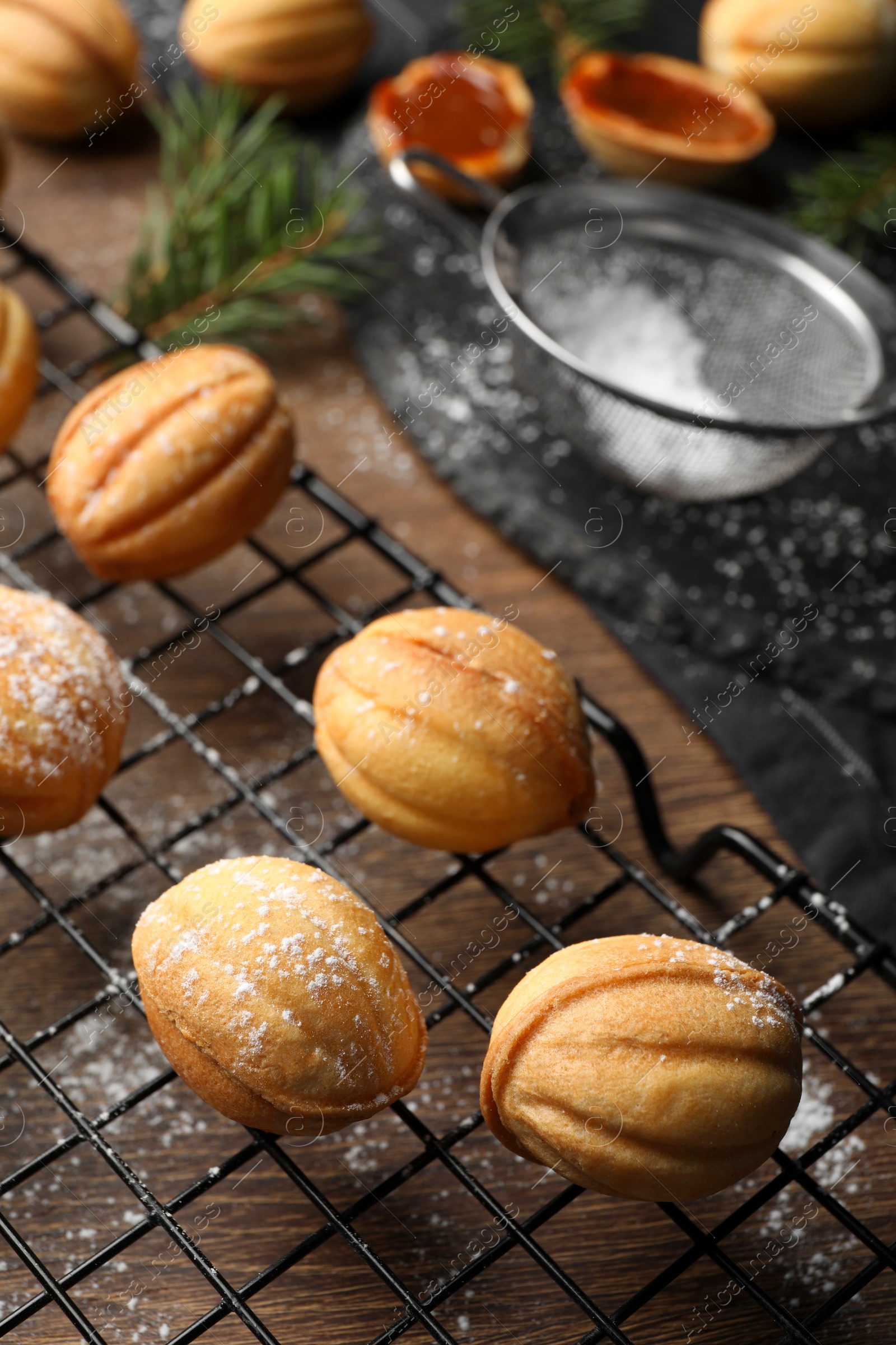 Photo of Delicious nut shaped cookies with powdered sugar on wooden table, closeup. Space for text
