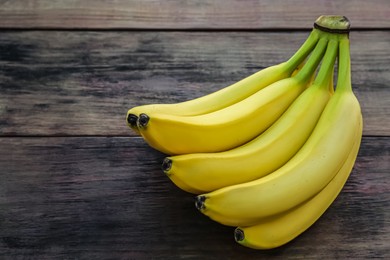 Photo of Bunch of ripe yellow bananas on wooden table