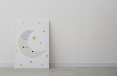 Adorable picture of moon and stars on floor near white wall, space for text. Children's room interior element