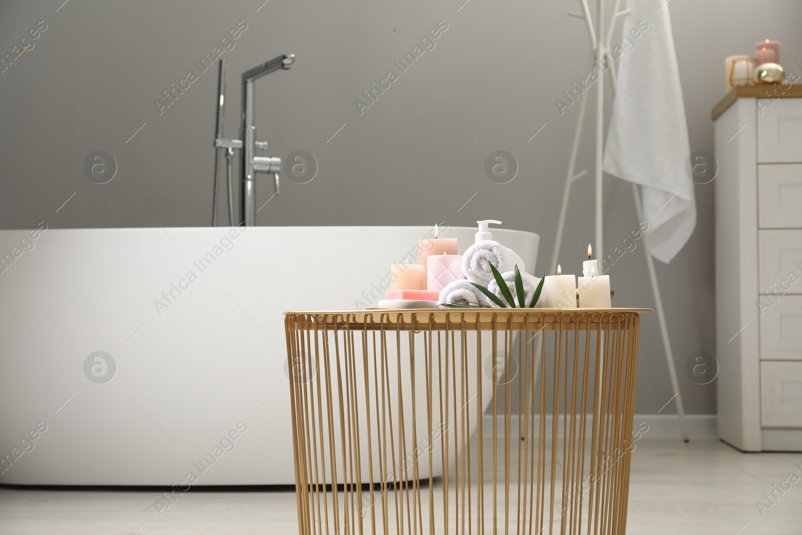 Photo of Stylish bathroom interior with ceramic tub and spa products on table