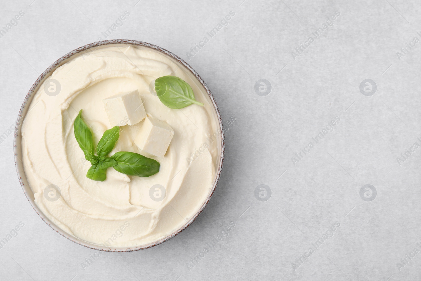 Photo of Delicious tofu sauce and basil leaves on light grey table, top view. Space for text