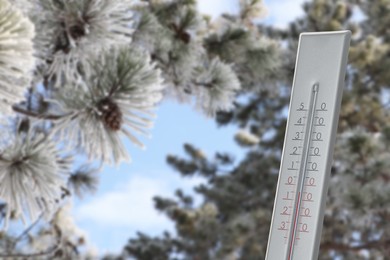 Image of Thermometer showing temperature in snowy forest, winter weather