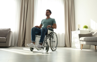 Photo of Young man sitting in modern wheelchair indoors