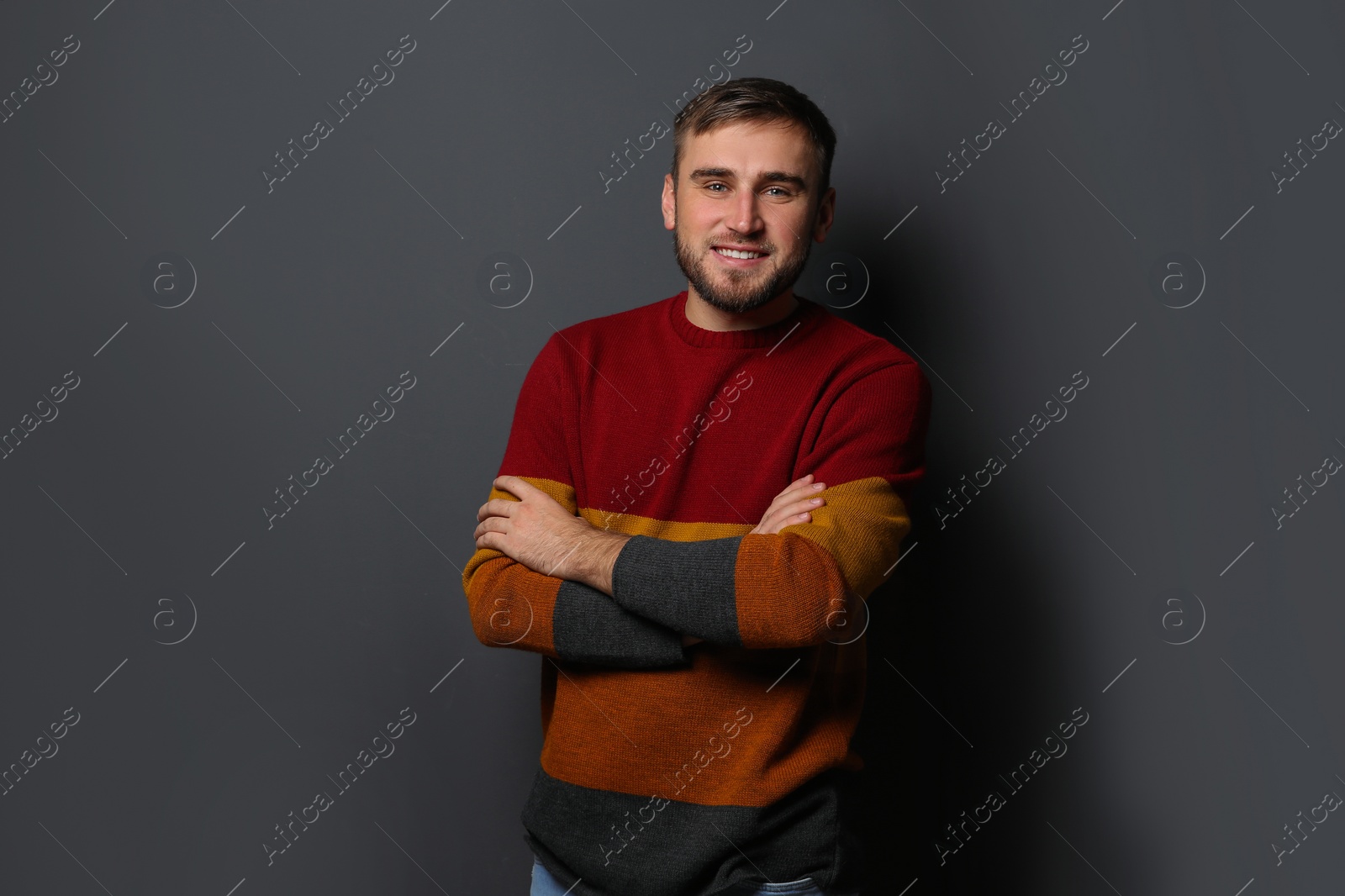 Photo of Handsome young man in warm sweater on dark background