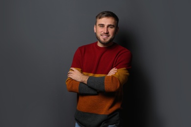 Handsome young man in warm sweater on dark background