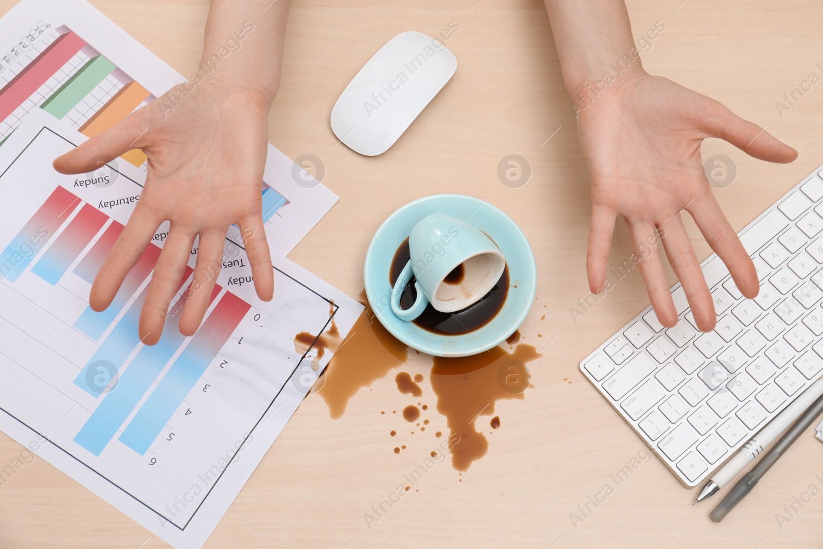 Photo of Closeup of woman spilled coffee on wooden office desk, top view