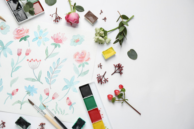 Photo of Flat lay composition with watercolor paints and floral picture on white background