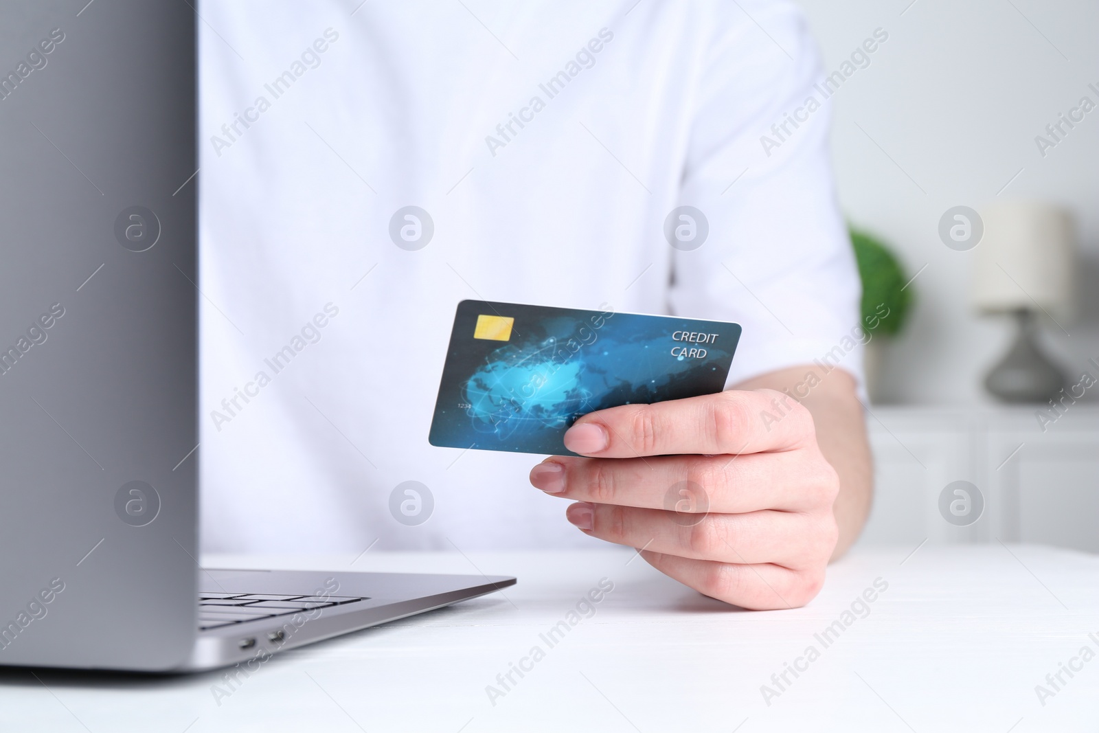 Photo of Online payment. Woman with laptop and credit card at white table, closeup