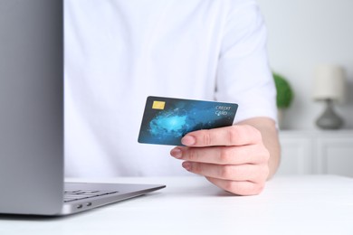 Photo of Online payment. Woman with laptop and credit card at white table, closeup