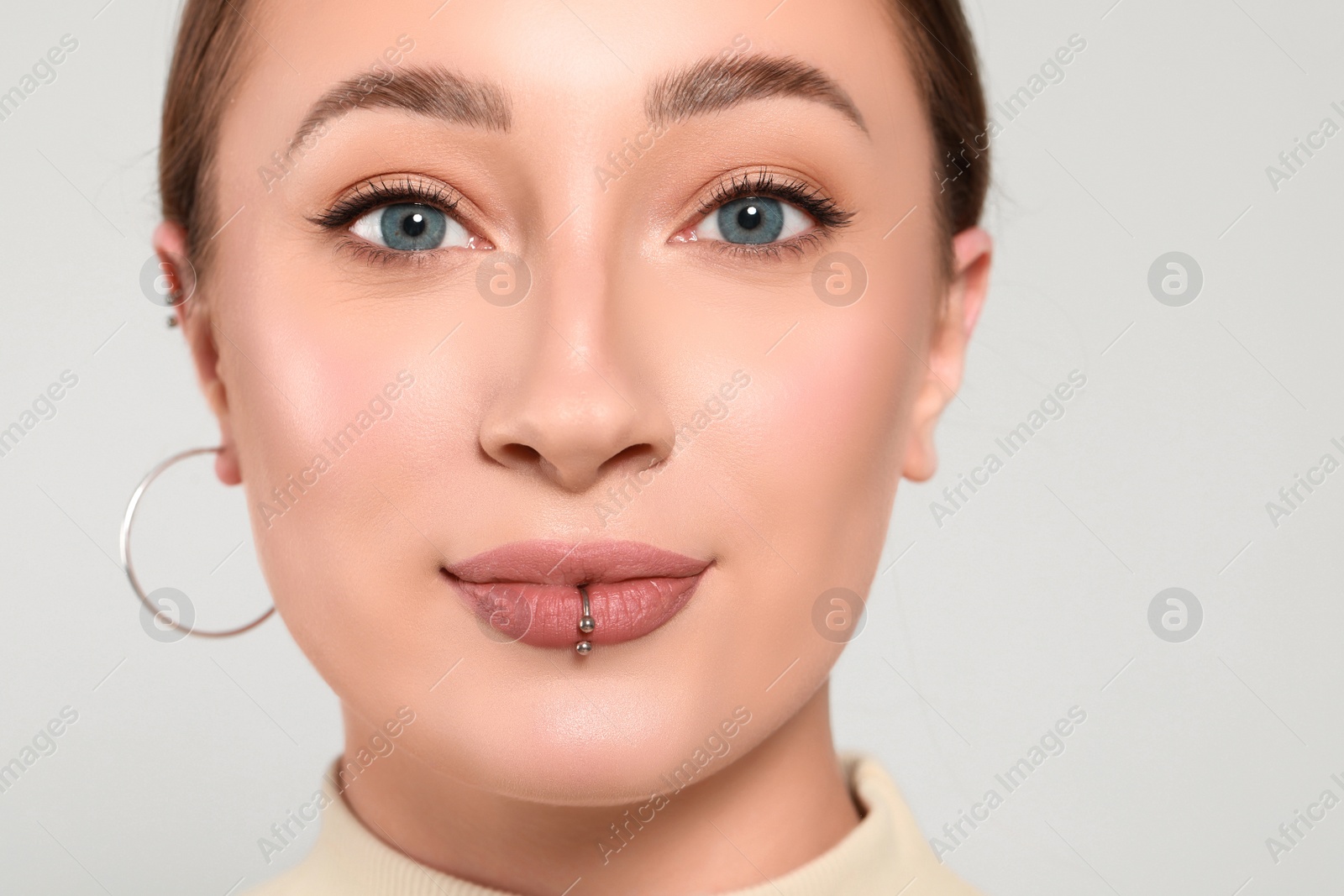 Photo of Young woman with lip piercing on white background, closeup