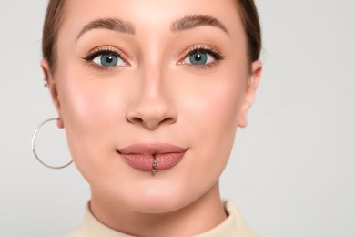 Photo of Young woman with lip piercing on white background, closeup