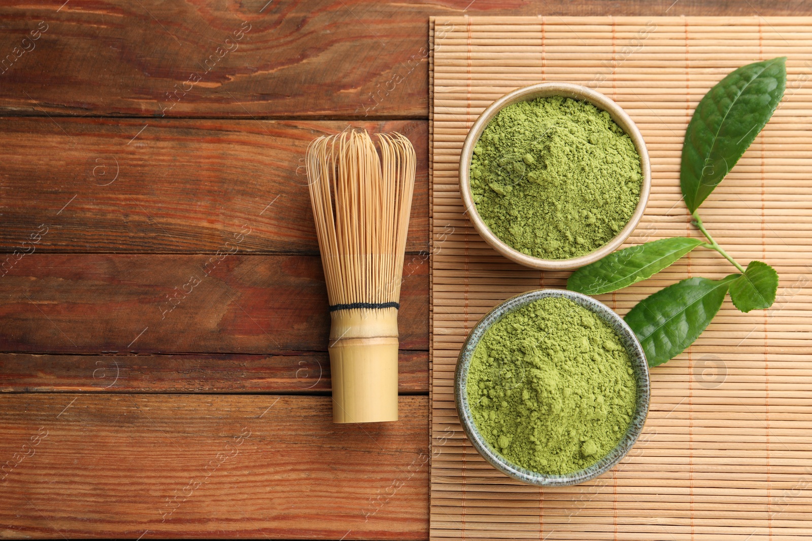 Photo of Green matcha powder and bamboo whisk on wooden table, flat lay. Space for text