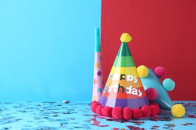 Photo of Party hats and confetti on color background, space for text