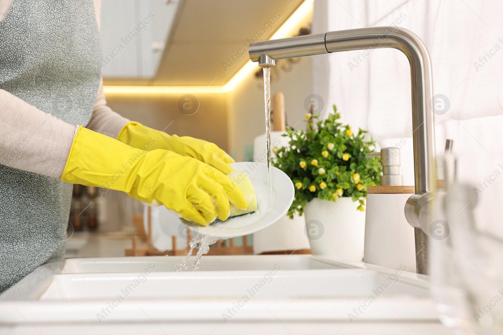 Photo of Housewife washing plate in kitchen sink, closeup