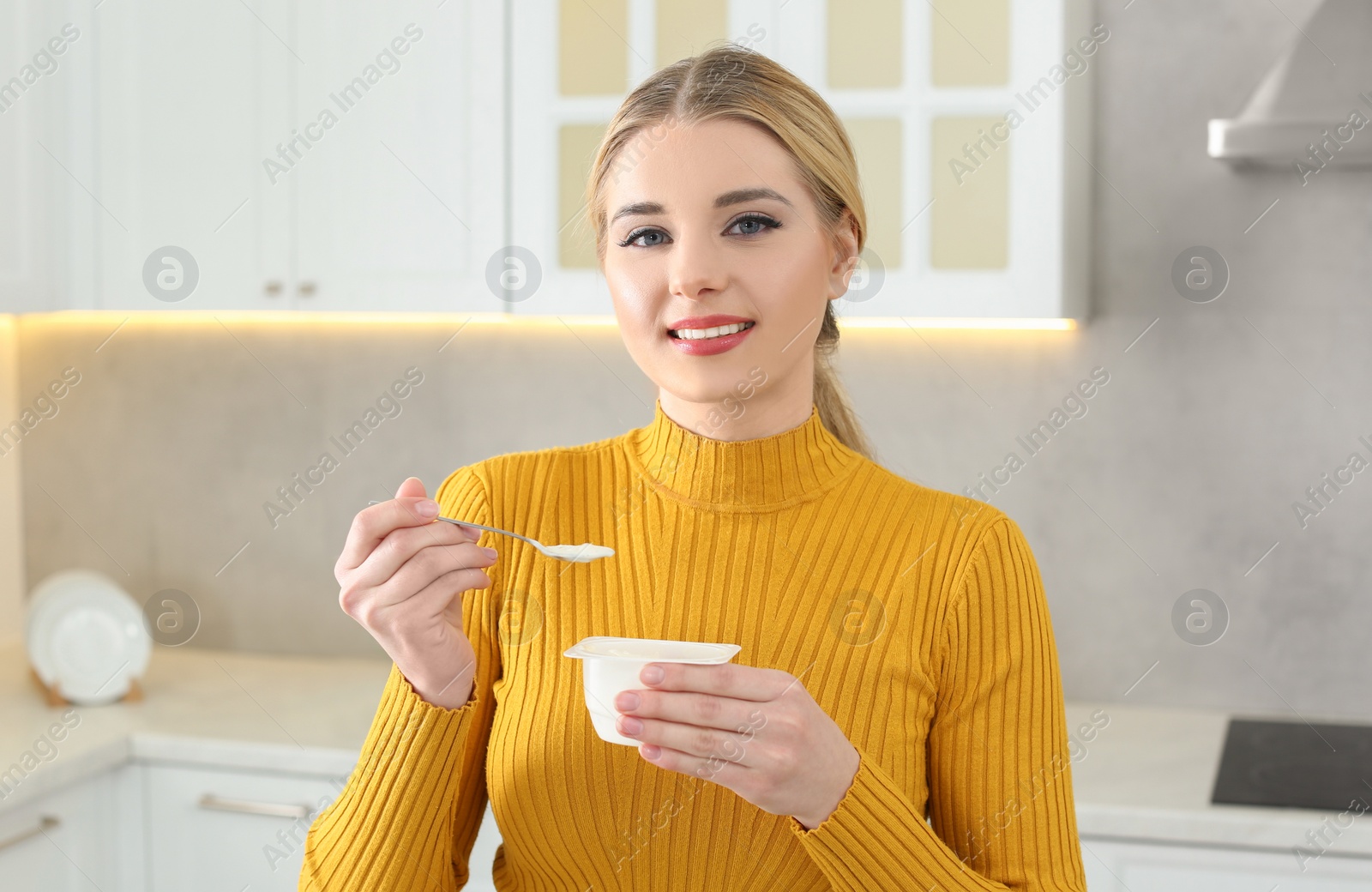 Photo of Portrait of happy woman with tasty yogurt in kitchen