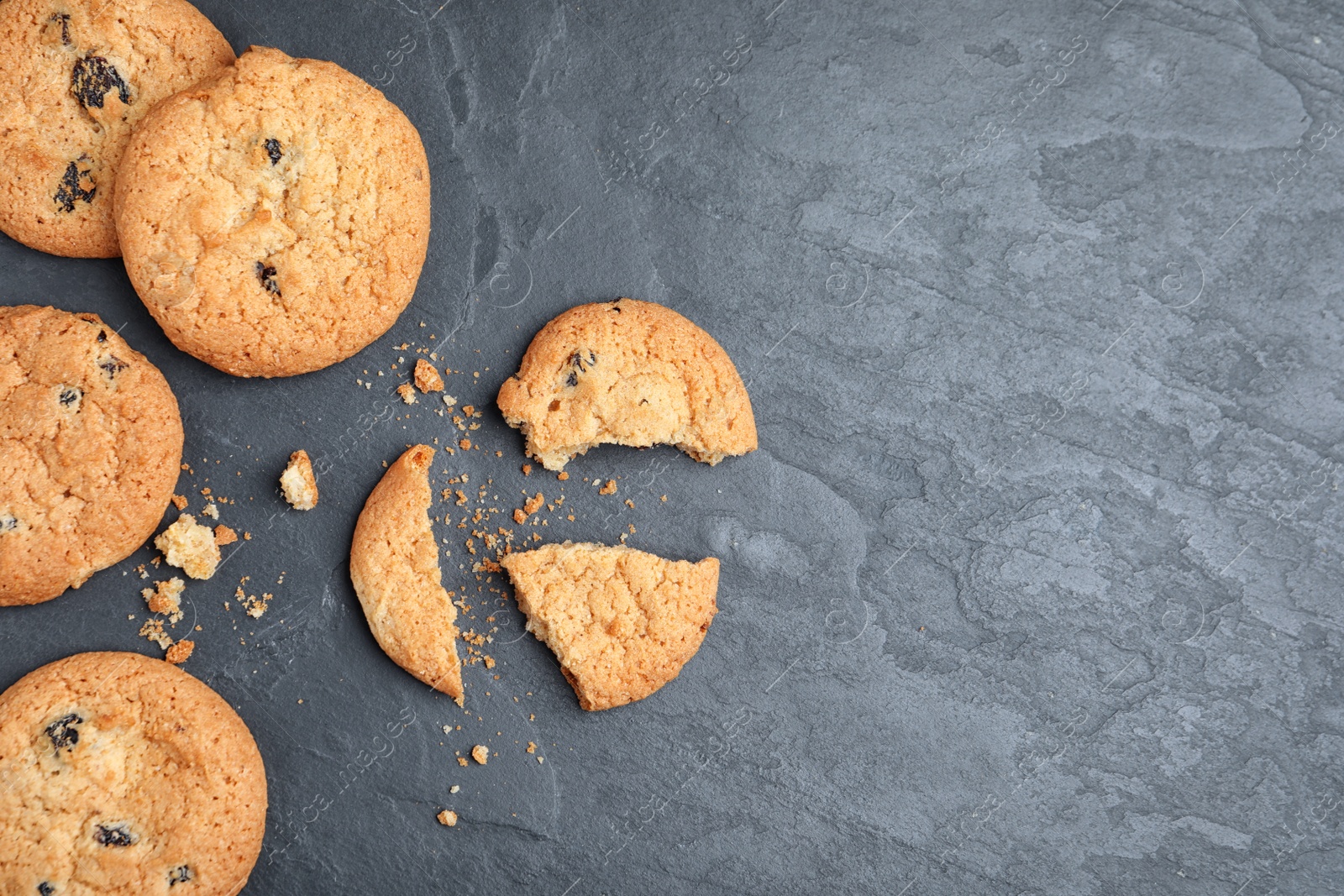 Photo of Delicious cookies with raisins on black table, flat lay. Space for text