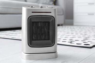 Photo of Modern electric fan heater on floor in living room