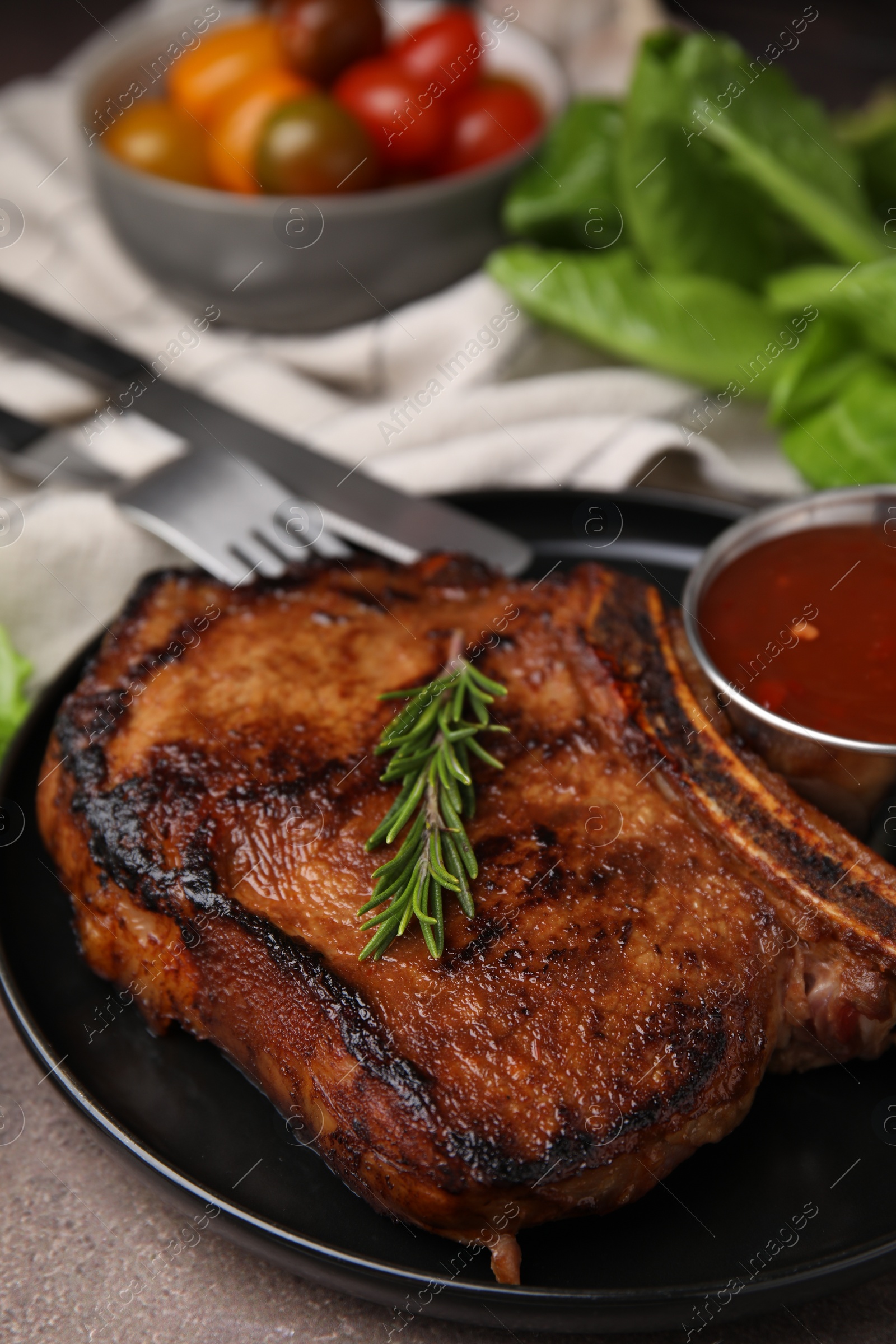 Photo of Tasty grilled meat, rosemary and marinade on brown textured table, closeup