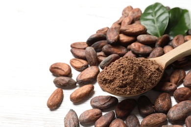 Photo of Composition with cocoa beans and powder on white wooden table, closeup. Space for text