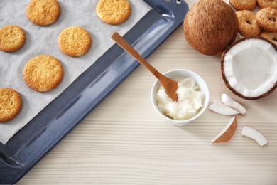 Photo of Bowl with coconut oil and cookies on wooden background