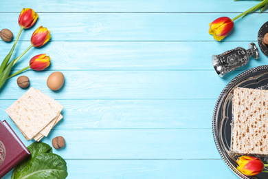 Flat lay composition with symbolic Pesach (Passover Seder) items on light blue wooden table, space for text