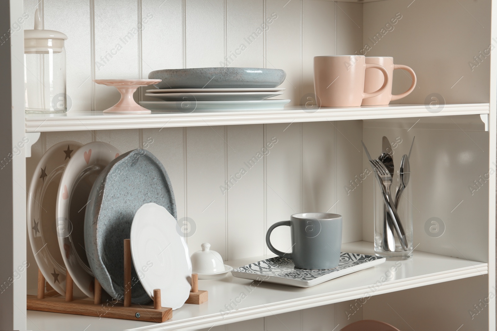 Photo of Stylish storage stand with different ceramic dishware at home