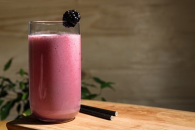 Photo of Glass of blackberry smoothie on wooden table. Space for text