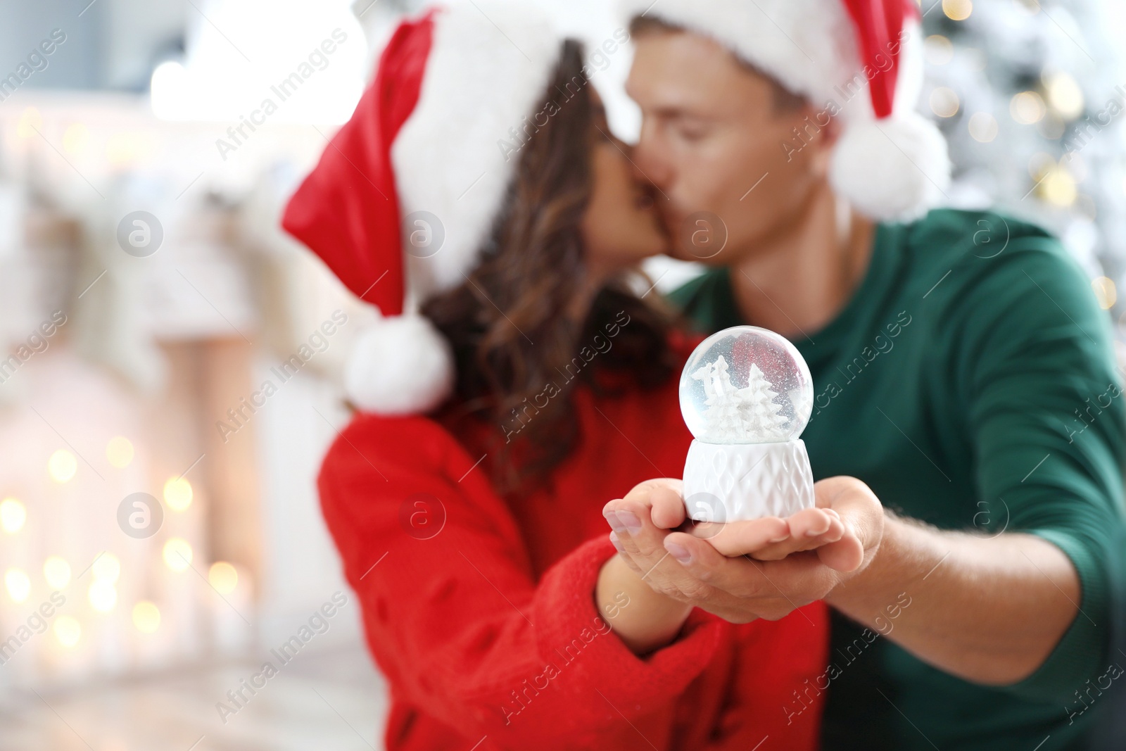 Photo of Happy couple at home, focus on hands with snow globe