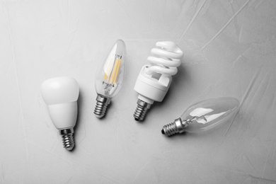 Different lamp bulbs on grey background, flat lay