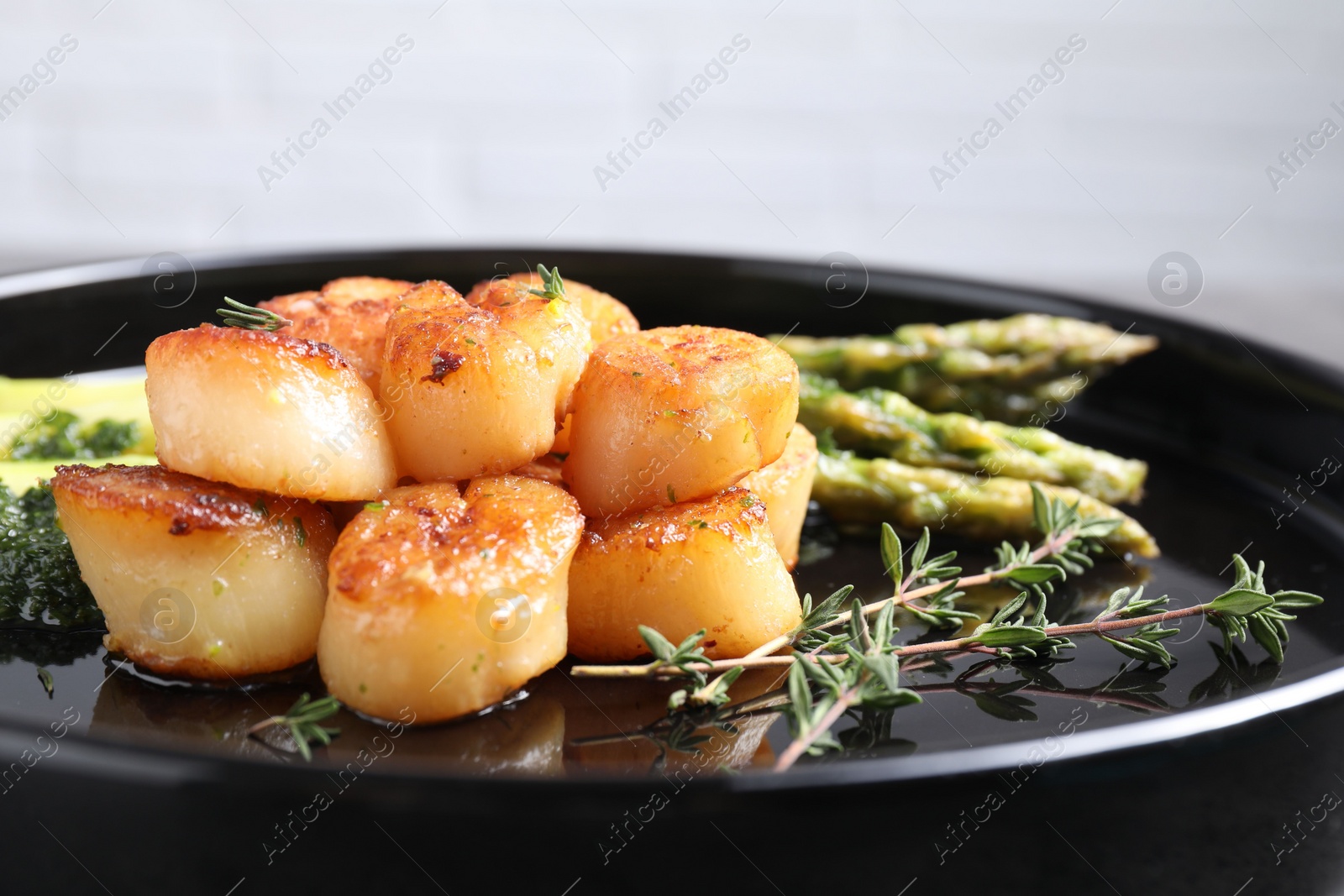 Photo of Delicious fried scallops with asparagus and thyme on plate, closeup