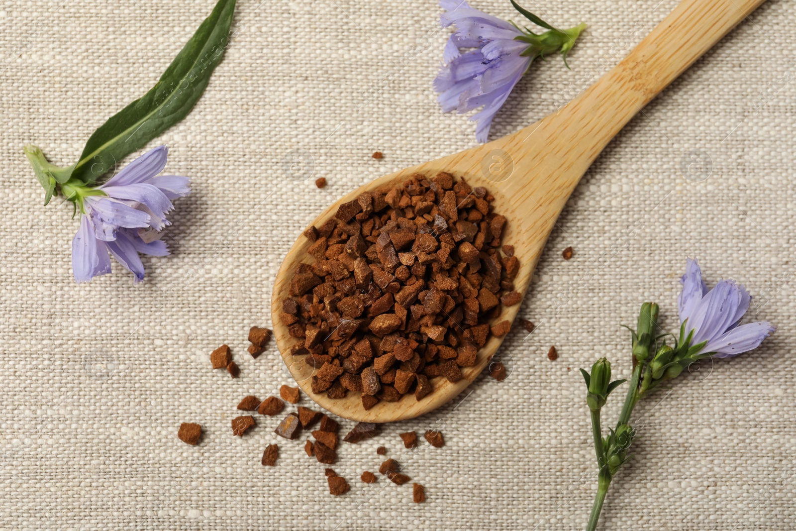 Photo of Spoon of chicory granules and flowers on sackcloth, flat lay