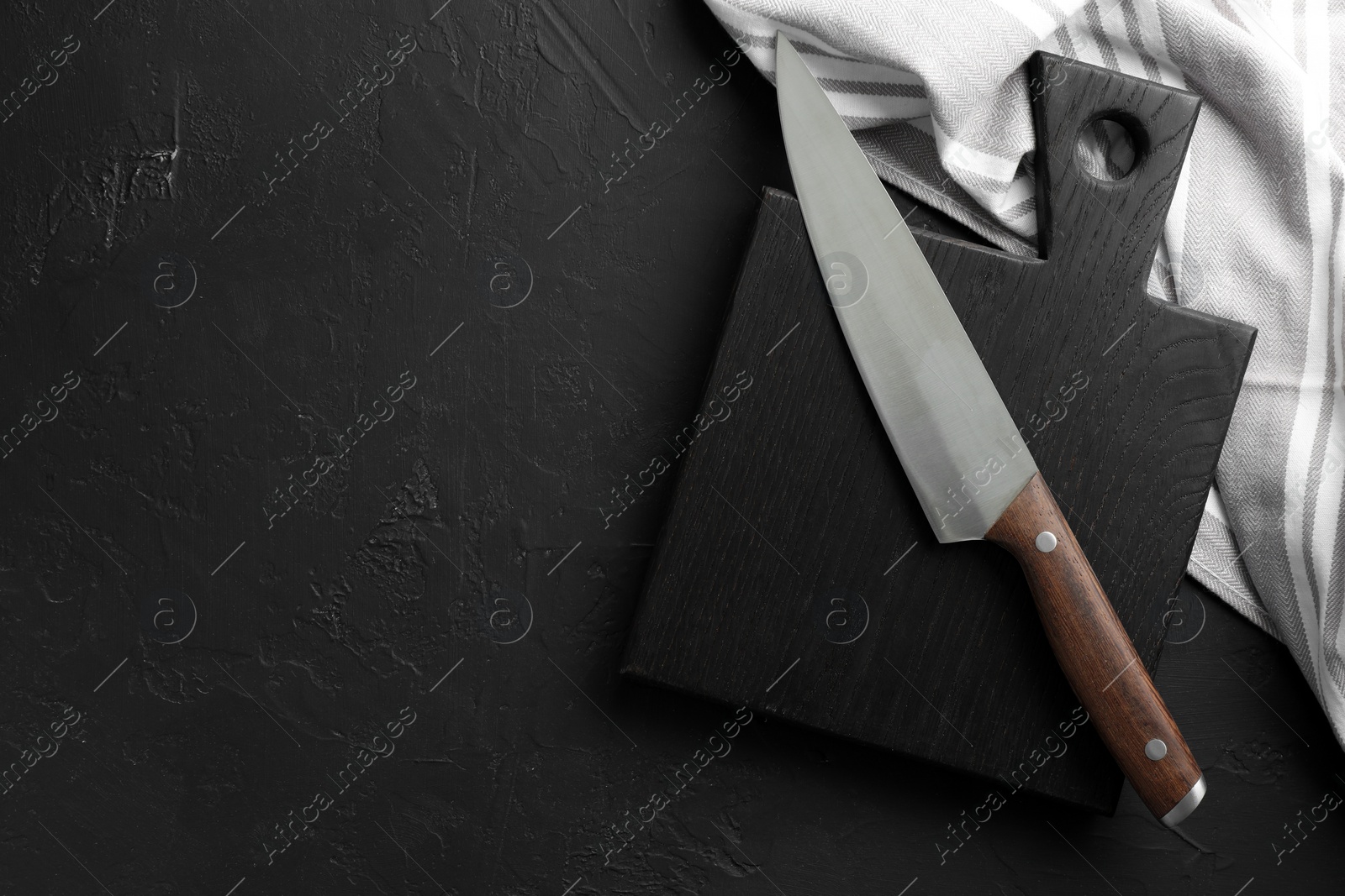 Photo of One sharp knife and board on dark textured table, top view. Space for text