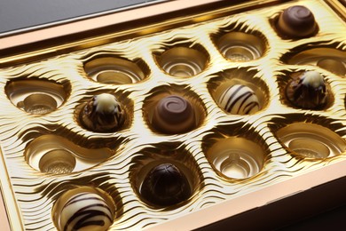 Photo of Partially empty box of chocolate candies on grey table, closeup
