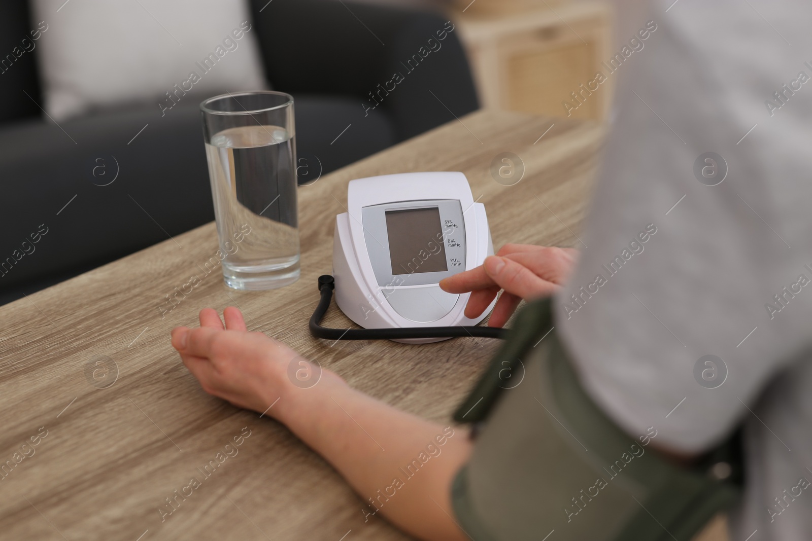 Photo of Woman checking blood pressure at wooden table indoors, closeup