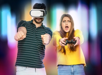 Photo of Man wearing VR headset and woman with controller playing video games on colorful background