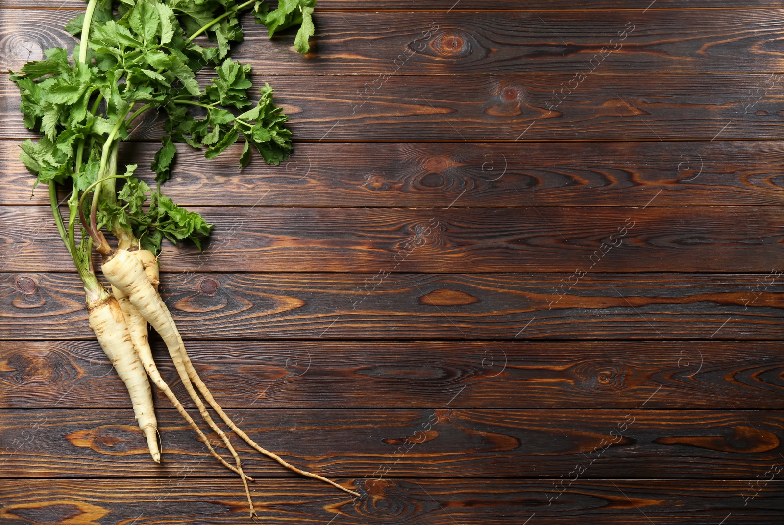 Photo of Tasty fresh ripe parsnips on wooden table, flat lay. Space for text