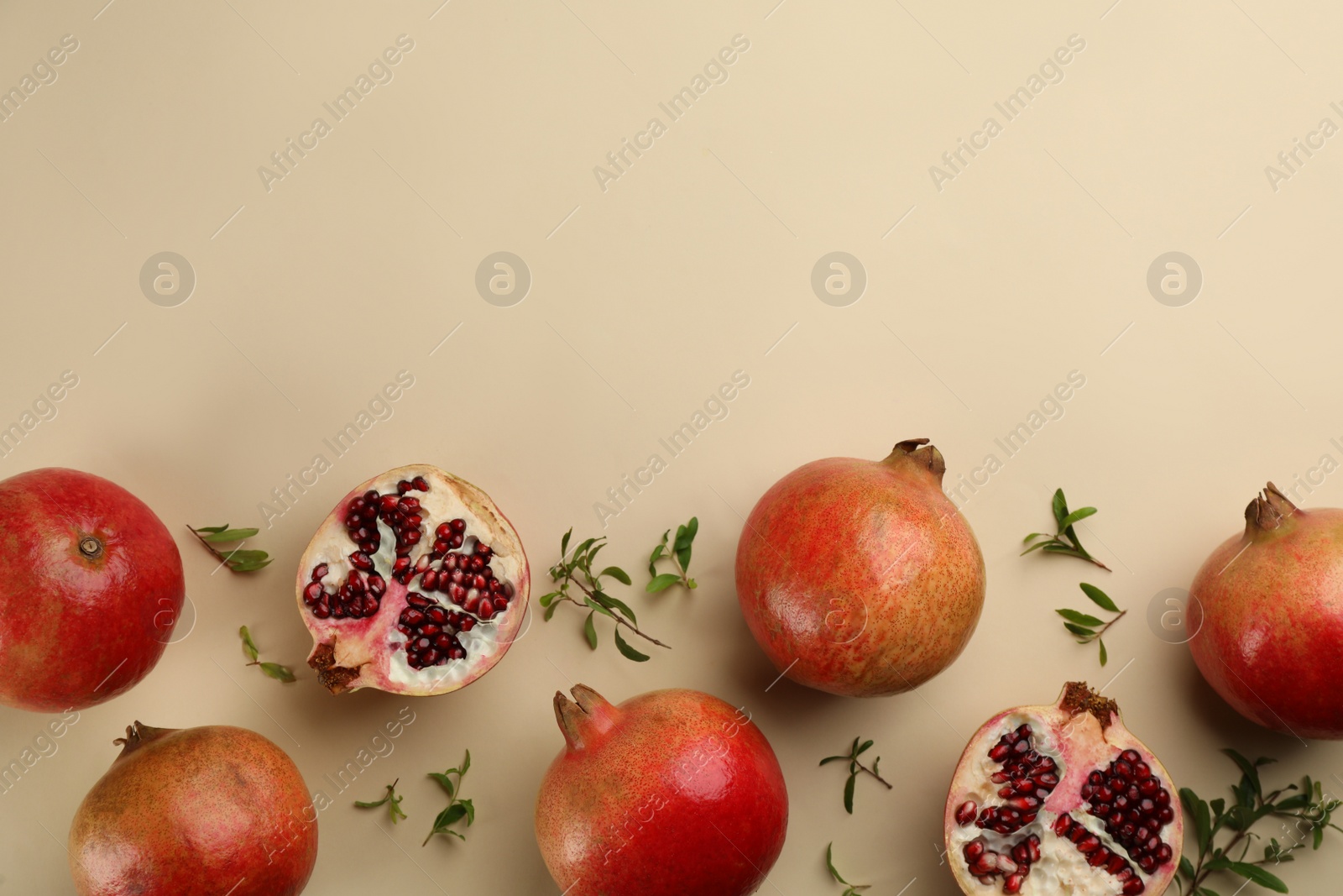 Photo of Flat lay composition with ripe pomegranates on beige background. Space for text