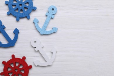 Photo of Anchor and ship wheel figures on white textured table, flat lay. Space for text