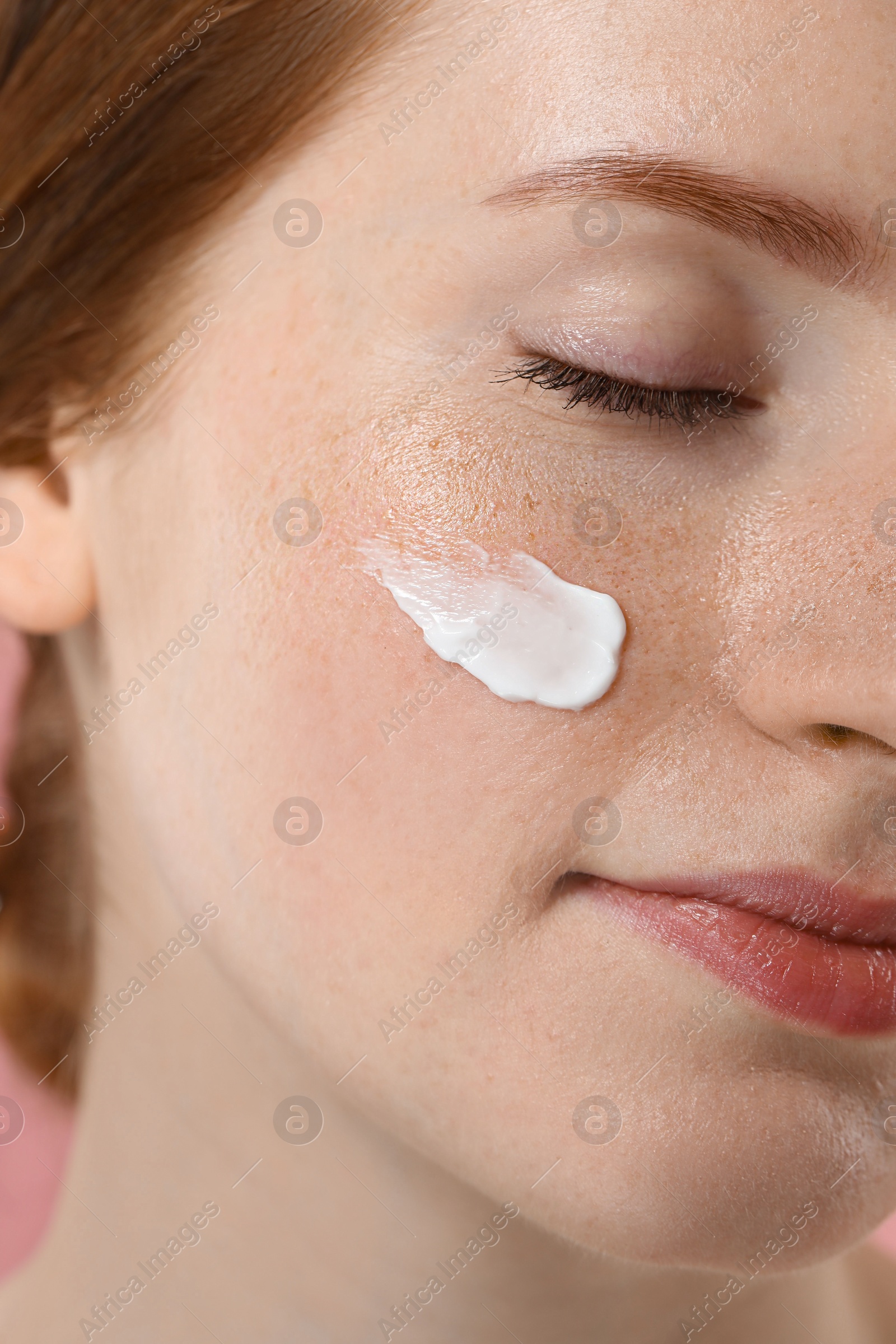 Photo of Beautiful woman with freckles and cream on her face, closeup