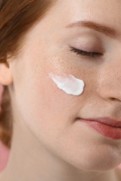 Beautiful woman with freckles and cream on her face, closeup