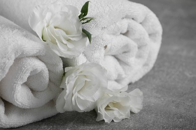 Photo of White soft towels with flowers on grey table, closeup