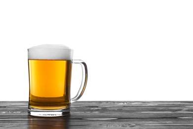 Glass mug of tasty beer on black wooden table against white background