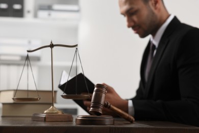 Photo of Law and justice. Judge working at wooden table in office, focus on gavel