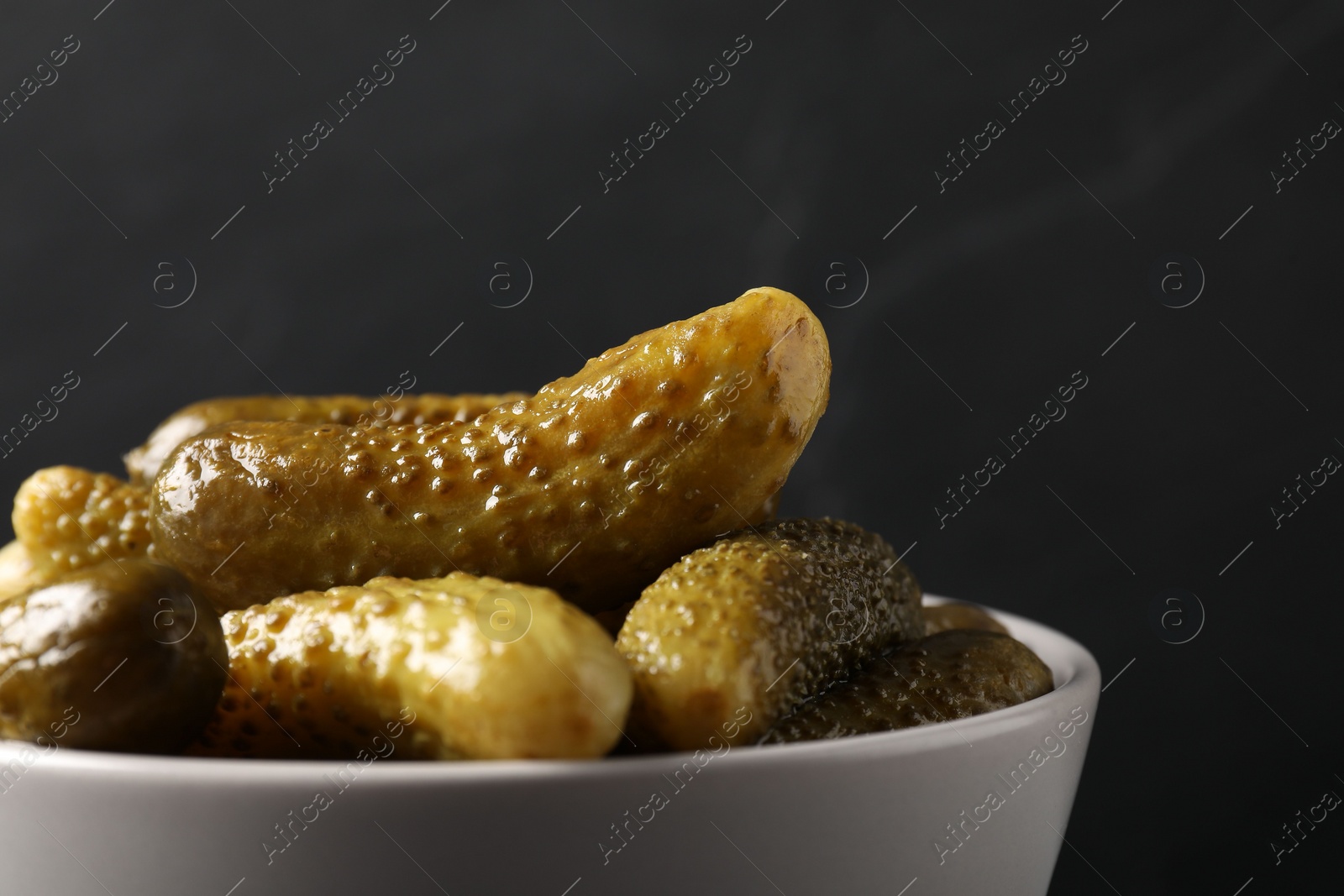 Photo of Tasty pickled cucumbers in bowl on grey background, closeup. Space for text