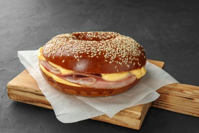 Delicious bagel with ham and cheese on grey table