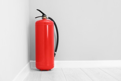 Photo of Fire extinguisher on floor indoors, space for text